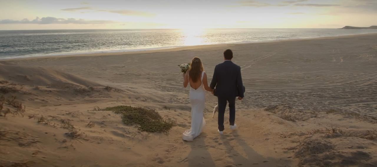 Newlyweds walking down the dunes toward the sea