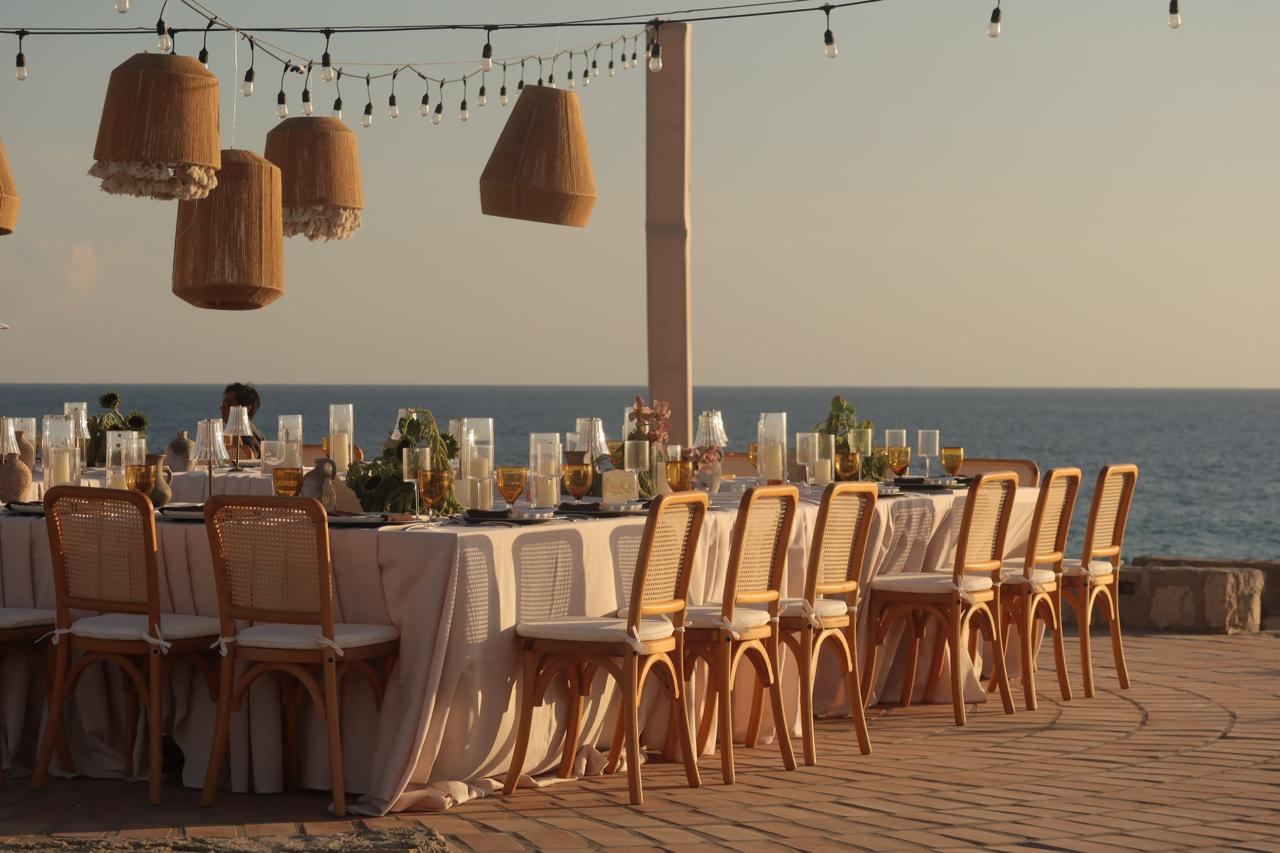 Rattan chairs along a dressed dinner table by the sea