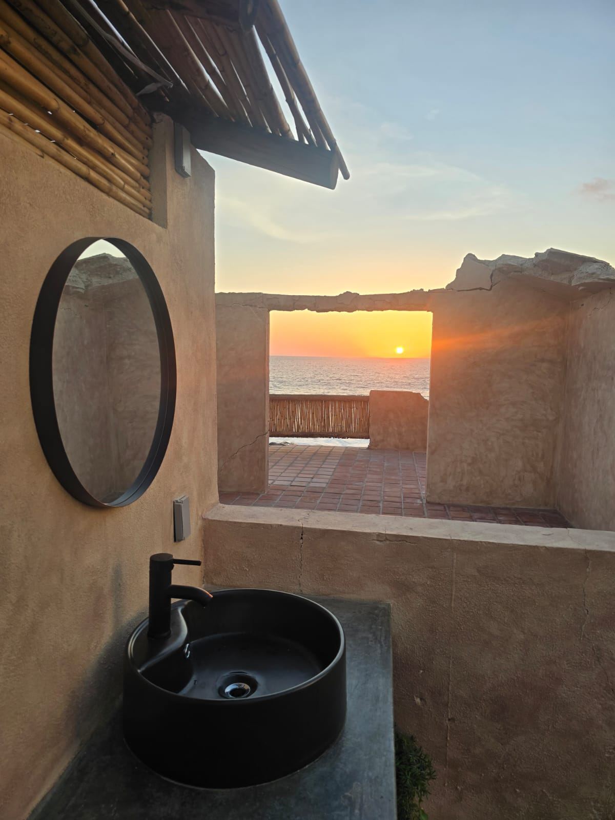 Open-air powder room with a sunset view through a stone opening